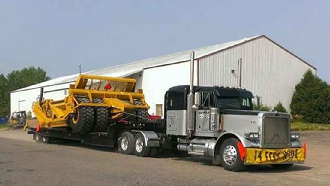 A flatbed trailer loaded with construction machinery.